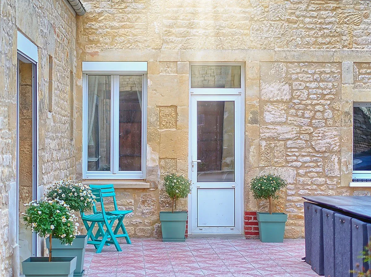 Façade en pierre et terrasse carrelée fleurie